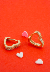 Con estos aretes huggies en forma de corazón vos llevás un aro dorado completamente forrado de cristales pavé que atrapan cada rayo de luz. Son livianos, hipoalergénicos y súper resistentes, perfectos pa’ darle un toque romántico y brillante a tu estilo diario o en ocasiones especiales. Descubrí vos cómo este diseño corazonado ilumina tu look con pura elegancia.